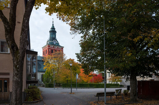 Church tower is visible among autumn trees on a street in Sala town, Sweden
