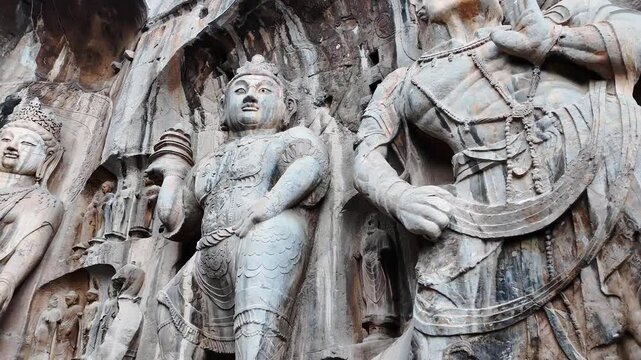 Luoyang Longmen, China: Dramatic footage of the famous statues and the Big Vairocana Buddha in the Longmen grottes Fengxian main cave that dates back from the 7th century. Shot with a pan motion