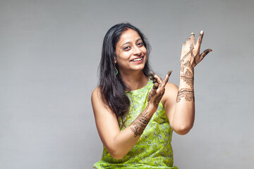 A joyful Indian woman showcasing her beautiful henna design in a dancing posture, captured during...