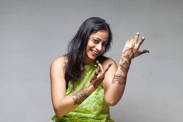 A joyful Indian woman showcasing her beautiful henna design in a dancing posture, captured during...