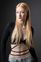 Portrait of a blonde woman with freckles in a sexy top and denim shorts in a studio.