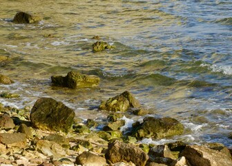 Seascape with porous rocks in the shallow water illuminated by the morning sun rays