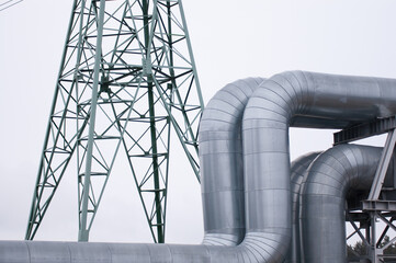 The photo shows a pipeline and a power line close-up against a gray sky