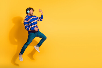 Full length photo of handsome young guy headphones play invisible guitar dressed blue striped garment isolated on yellow color background