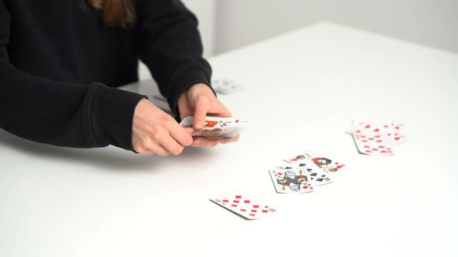 Hands of a young woman dealing classic cards from a deck for playing solitaire at a table. The concept of board card games, having fun, entertainment, poker.