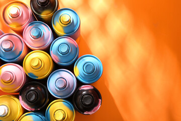 Different spray paint cans on orange background