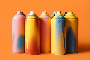 Different spray paint cans on orange background