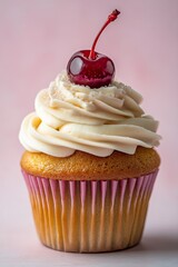 Delicious vanilla cupcake topped with cream frosting and a cherry on pink background