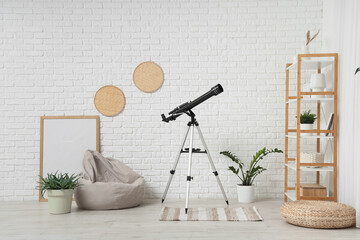 Interior of living room with beanbag chair, houseplants and modern telescope