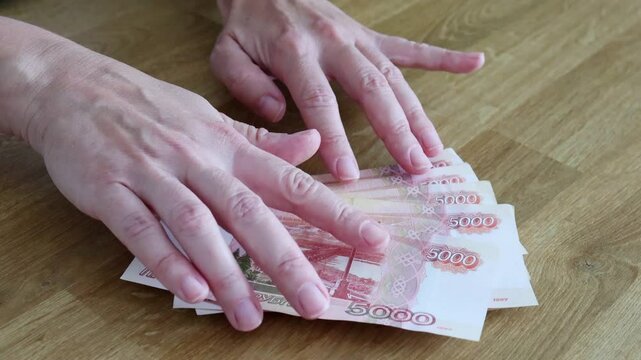 The currency of Russia. Close-up of Russian rubles. Financial concept. The background and texture of banknotes. The woman considers banknotes with a face value of 5,000 rubles.