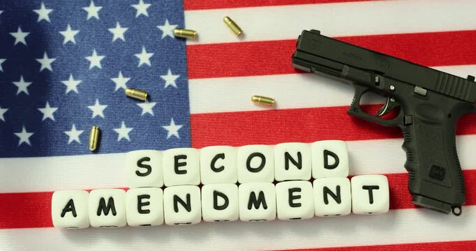 Bullets and handgun placed on American flag with phrase Second Amendment from cubes. Concept of guaranteed right gives ability to defend