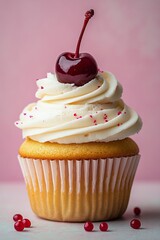 Delicious vanilla cupcake topped with cream frosting and a cherry on pink background
