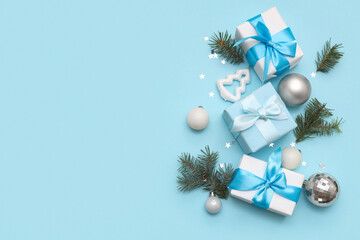 Festive composition with gift boxes, fir branches and Christmas baubles on blue background