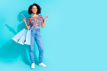Full body photo of pretty young girl device shopping point empty space wear trendy colorful clothes isolated on aquamarine color background