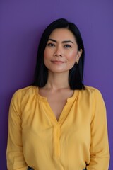 Fototapeta premium Confident Smiling Woman in Pastel Yellow Blouse Against Bold Purple Background for Portrait Design
