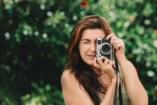 Woman capturing moments with a retro style camera outdoors