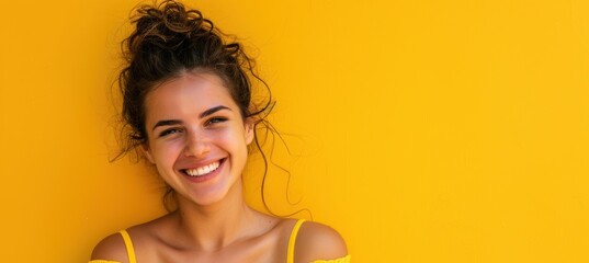 Obraz premium Joyful Young Woman with Radiant Smile on Vibrant Yellow Background for Print Design