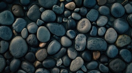 Smooth dark gray pebbles on a beach create a natural texture. Tranquil backgrounds and spa themes