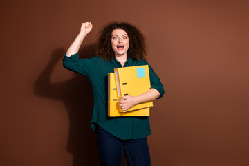 Photo of adorable lucky woman wear formal shirt holding documents folders empty space isolated brown color background