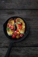toast with fried cherry tomatoes in a cast iron frying pan