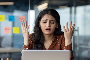 Experienced latino businesswoman feeling frustrated at work, facing challenges with laptop, raising...