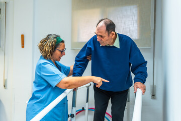 Nurse helping a senior man to walk on parallel bars