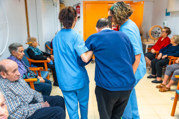 Nurses helping a man in the gym of a geriatrics