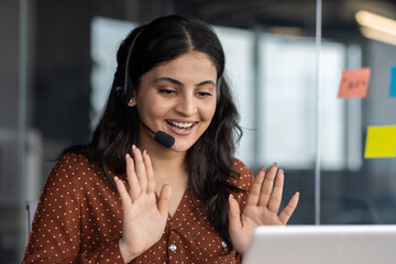 Latino businesswoman wearing headset engaging enthusiastically in virtual meeting at modern office...