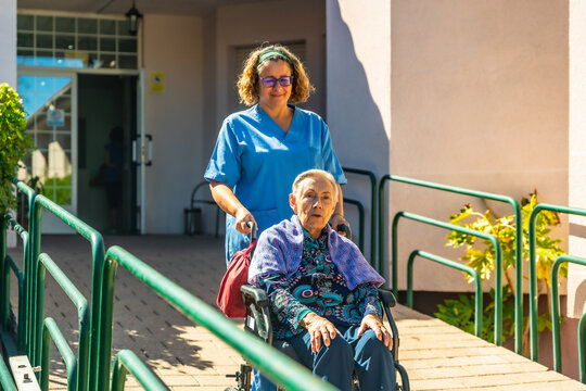 Nurse caring a senior woman in a wheelchair at garden