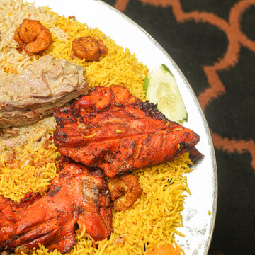 Close-up on Arabian assorted grill mandi with a side of sauces and vegetables