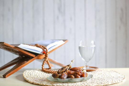 Display of a Misbaha on the Quran next to a glass of water and a plate of dates at iftar time