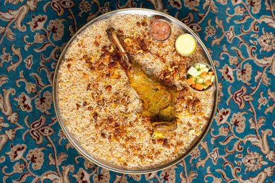 Flat lay of Arabian chicken mandi dish with vegetables and sauces