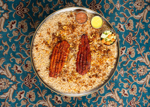 Flat lay of Arabian chicken mandi dish with a side of vegetables and sauces