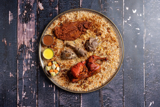 Flat lay of Arabian assorted grill mandi with a side of sauces and vegetables