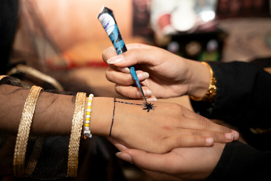 Henna artist drawing on on woman's hand