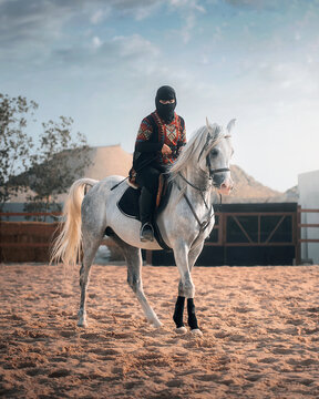 Woman wearing a niqab riding on white horse