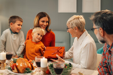 Family celebrating thanksgiving giving presents at dinner table