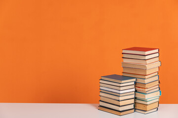 Stacks of educational books for library learning as an orange background