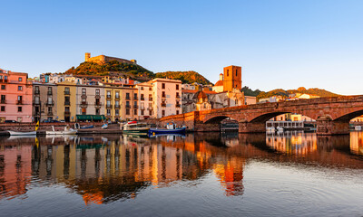 Obraz premium Beautiful view of the picturesque town of Bosa with its colorful houses reflected in the Temo River during golden hour, Sardinia, Italy.