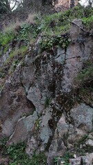 Rocky wall in Sant'Andrea, Italy, formed during road construction. Red-orange inclusions in rock...