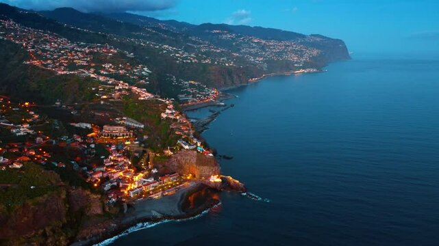 Amazing view of the picturesque city on the slope of the mountain. Stunning twilight scenery of Madeira, Portugal at the coast of the Atlantic Ocean. Top perspective.