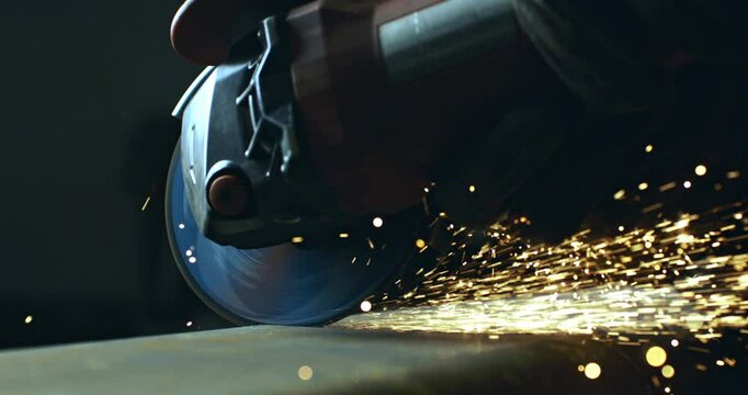 Super slow motion macro of blacksmith welder is working metal steel with industrial angle grinder with flying sparks in workshop at 1000 fps.