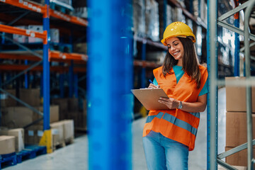 Female warehouse worker checking inventory using clipboard
