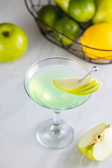 Green apple cocktail being poured into a martini glass
