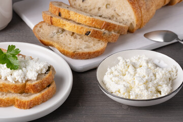 Creamy cottage cheese served with slices of whole grain bread on a wooden table in a cozy kitchen setting