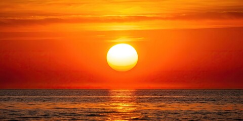 Scenic sunrise over orange sky and sea with white hot sun, tilted angle