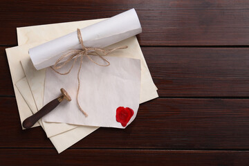 Old letters, wax stamps and envelopes on wooden table, top view. Space for text