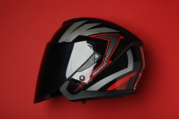 Fototapeta premium Modern motorcycle helmet with visor on red background, top view