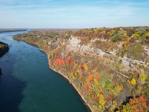 Aerial over the Niagara River and gorge between Lewiston, New York, United States and Ontario, Canada towards Lake Ontario. Shot during an autumn afternoon with colorful fall foliage trees in October.