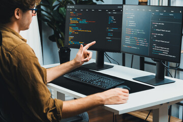 IT developer working online software development on pc monitors at modern home office on coding...